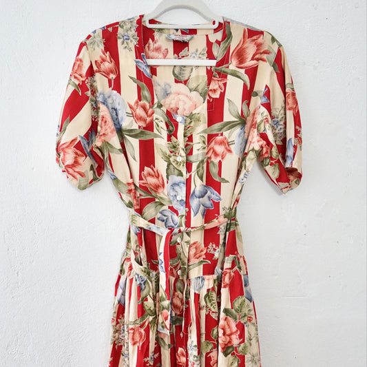 Floral dress with red and white pattern on a hanger against a white background